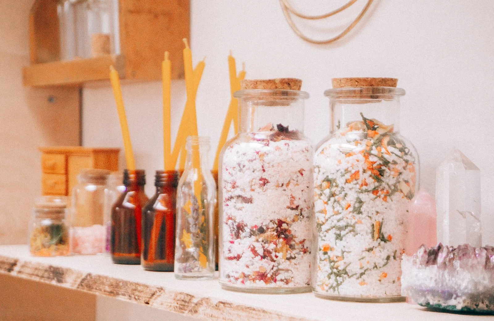 Amethyst cluster and pointed crystal ornaments beside decorative jars and unlit candles on a shelf
