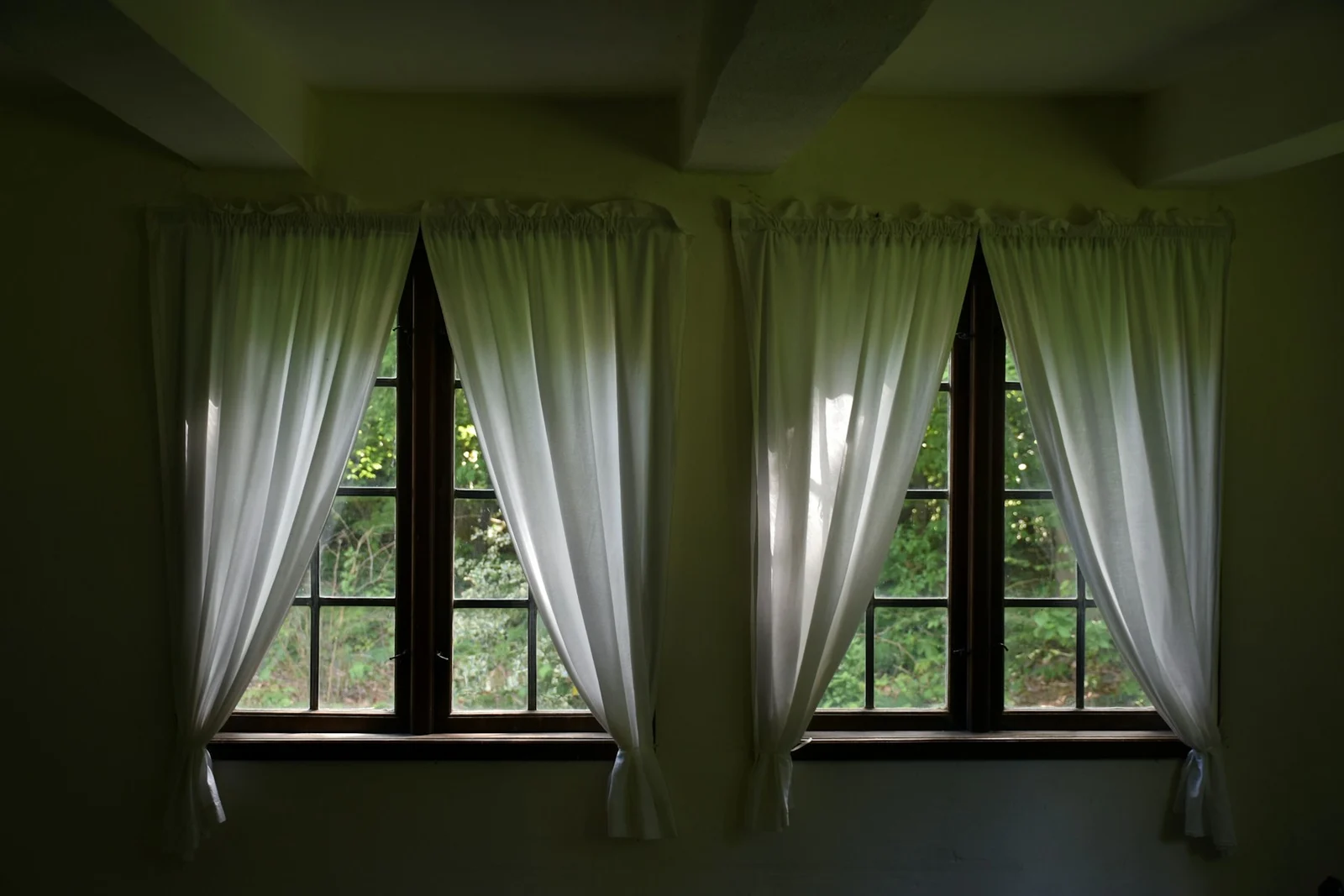 White sheer curtains tied beside two timber-framed windows