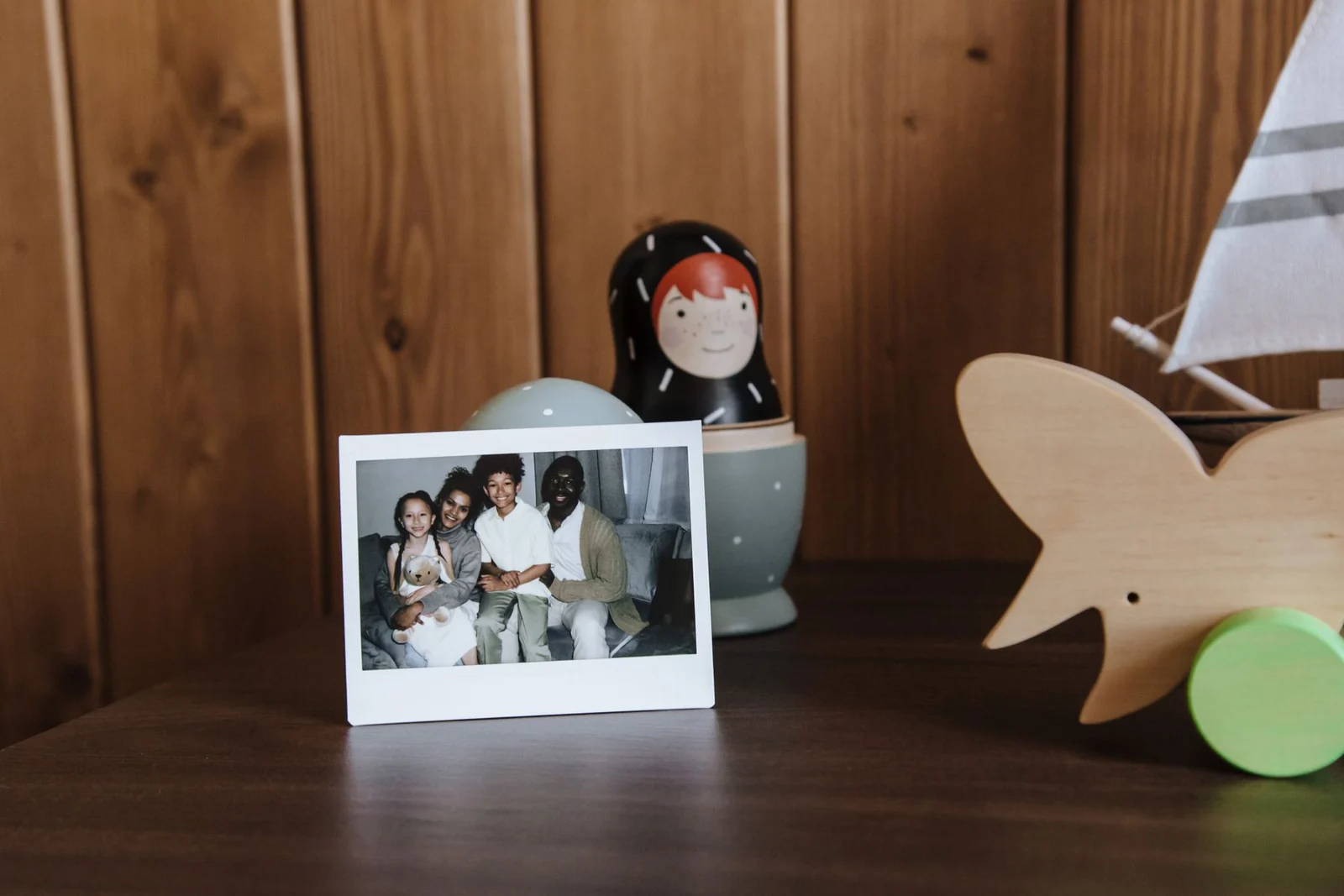 Small white frame containing a family photograph on a wooden dresser beside toys