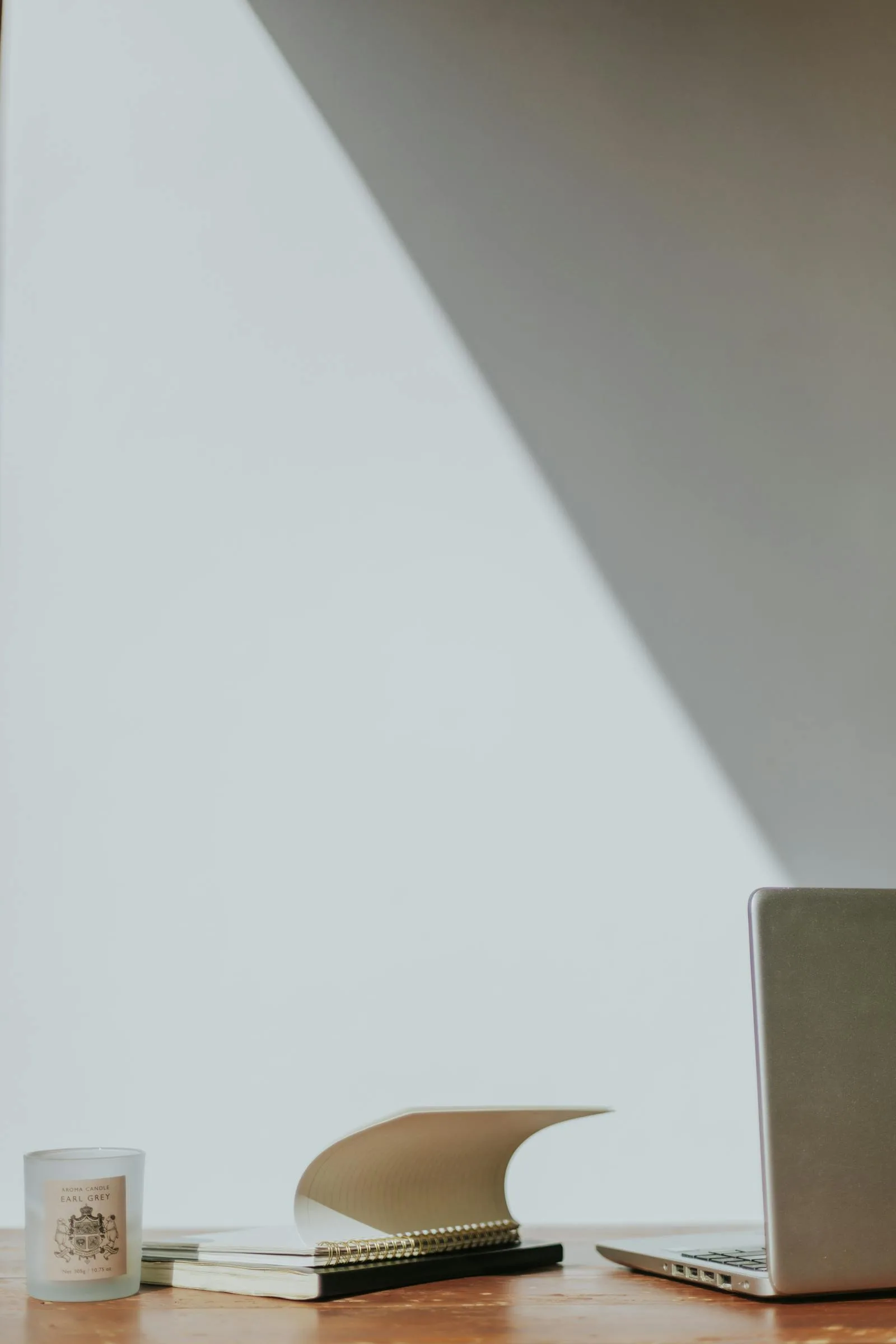 Minimal desk corner with laptop, candle, notebook, and calm negative space