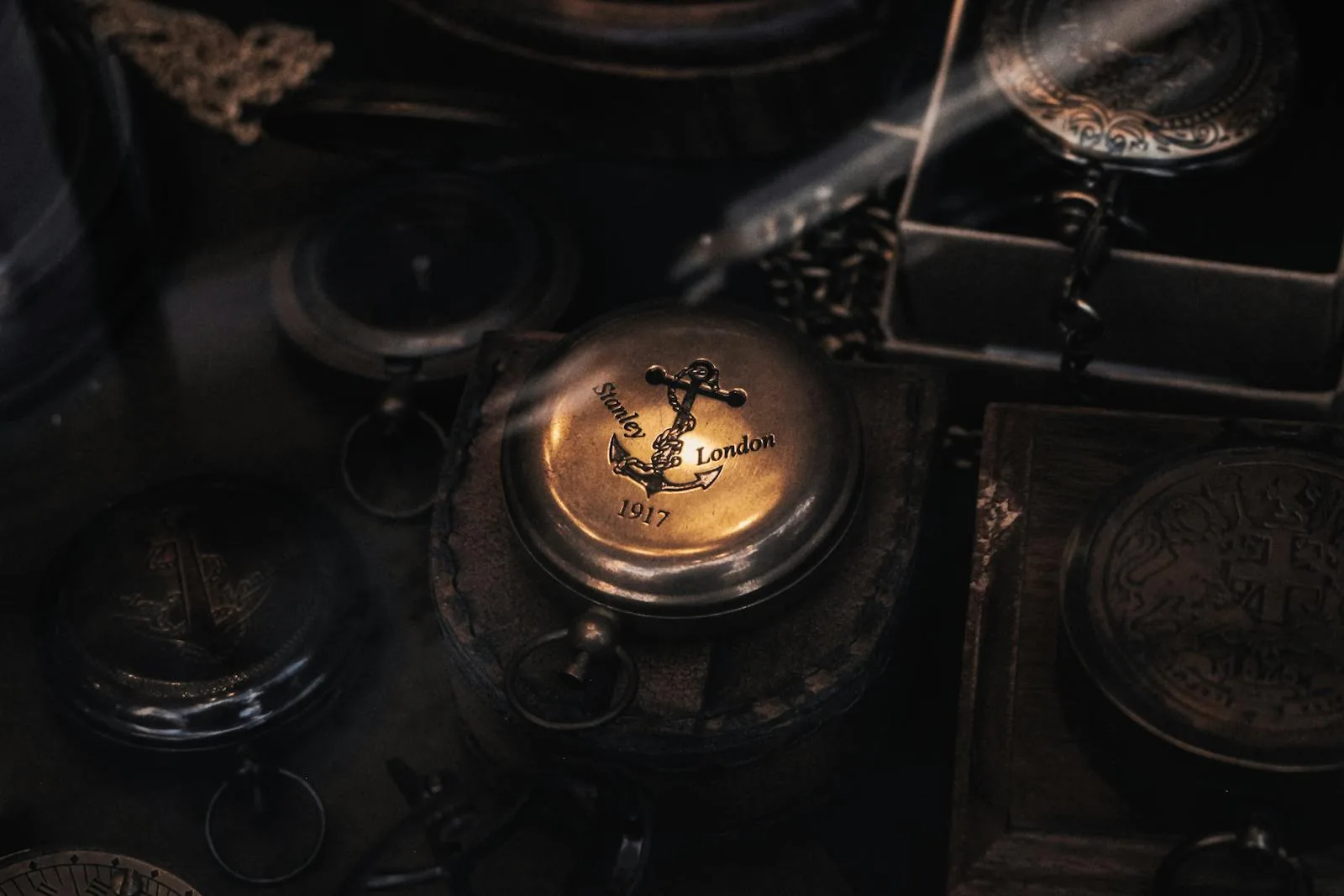 Hand holding a brass compass outdoors with greenery in the background