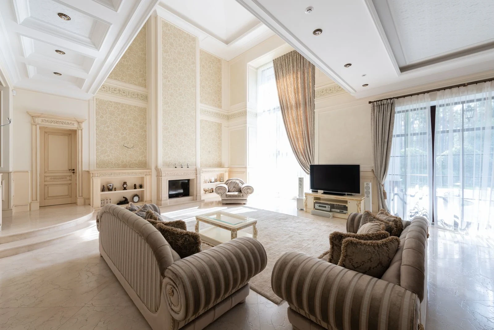 Living room with two sofas, a fireplace and a television between tall curtained windows
