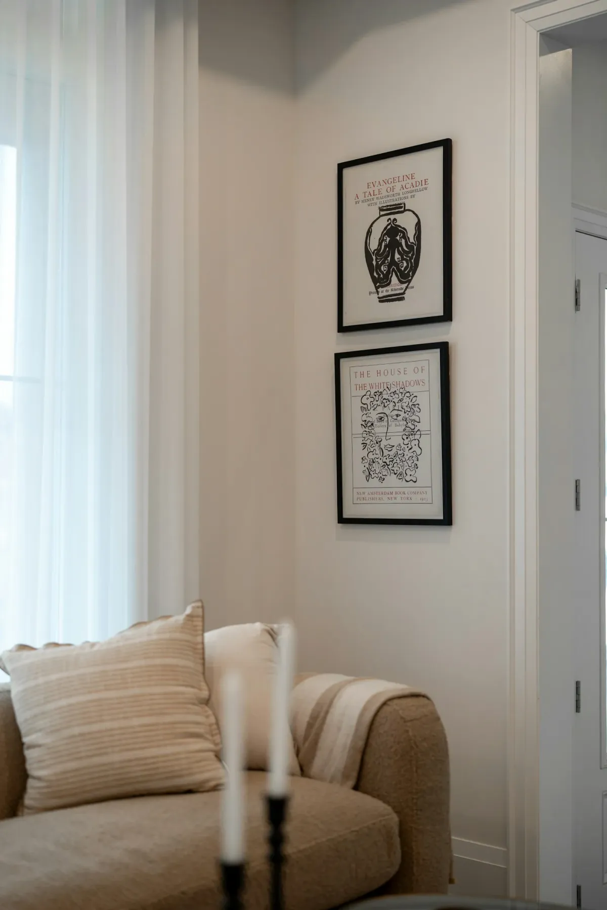 Vertical pair of framed artworks beside a doorway and sofa