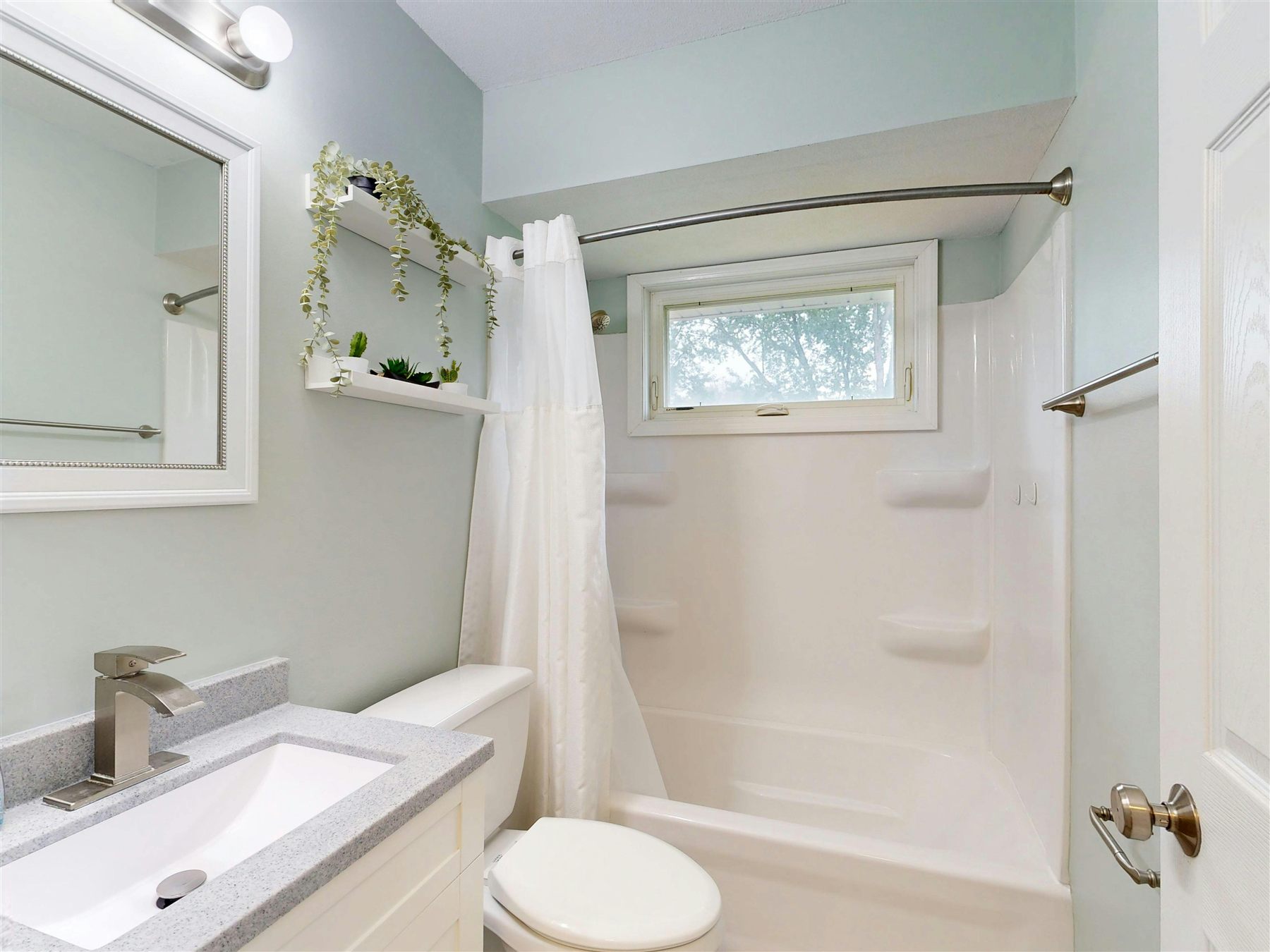 Fresh bathroom with pale sage walls, white shower curtain, and a bright clean layout