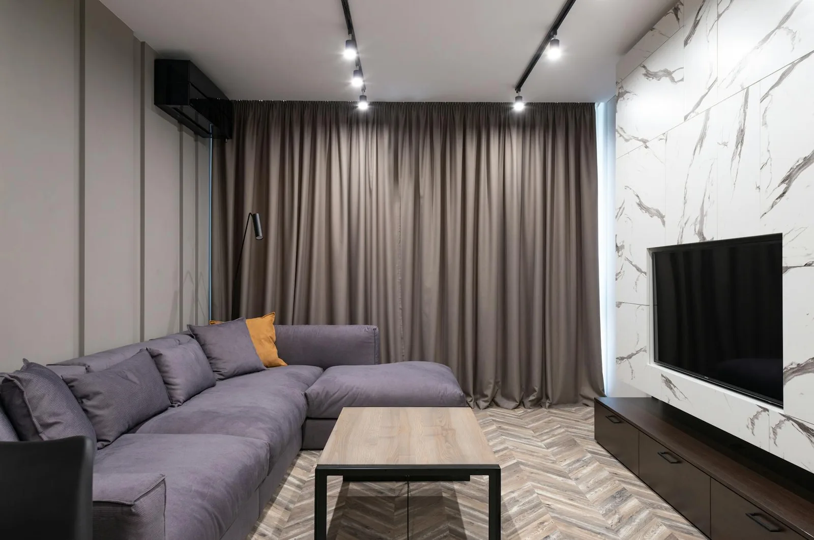 Small apartment living area with sofa, curtain wall, TV wall, and closed low storage