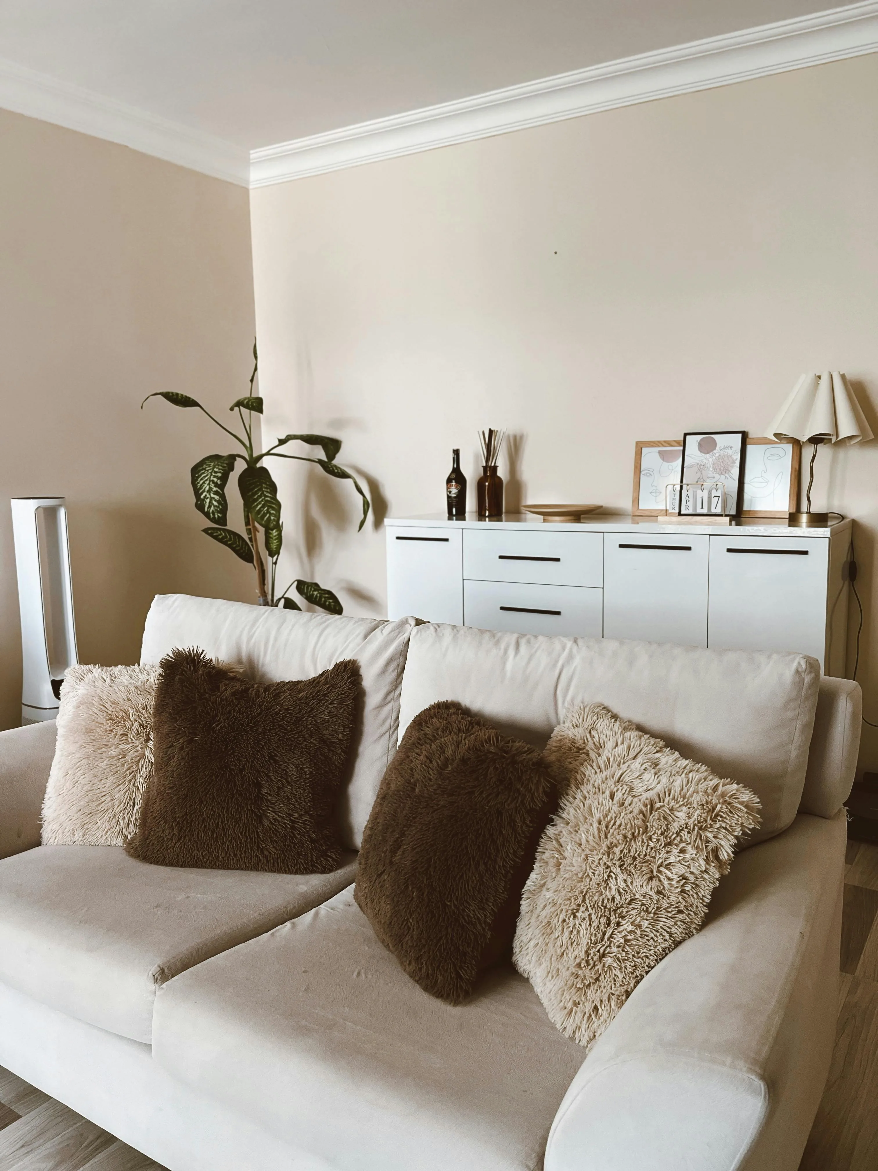 Soft neutral living room with warm daylight, simple furnishings, and a quieter imperfect mood