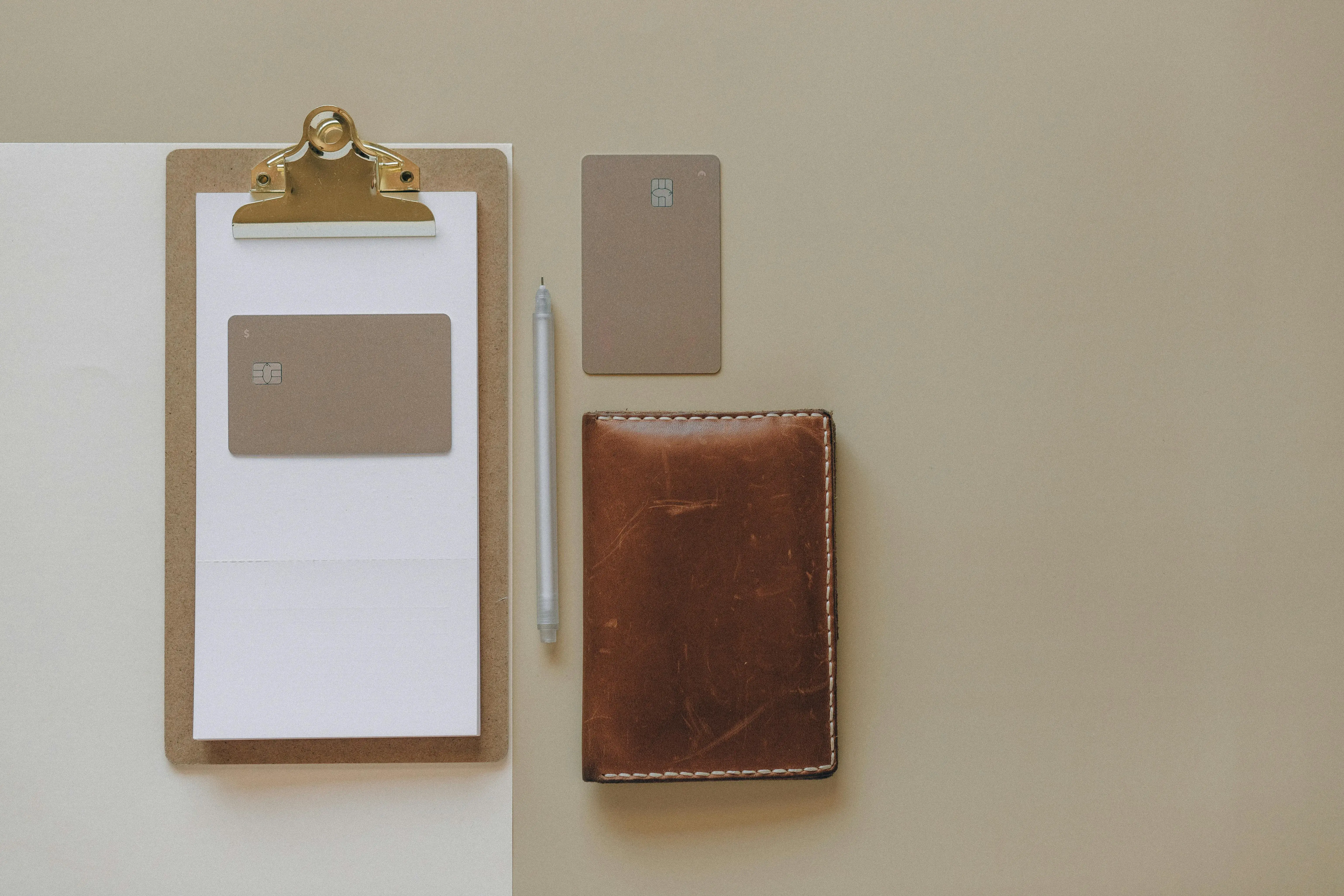 Wallet, cards, clipboard, and pen arranged neatly on a desk
