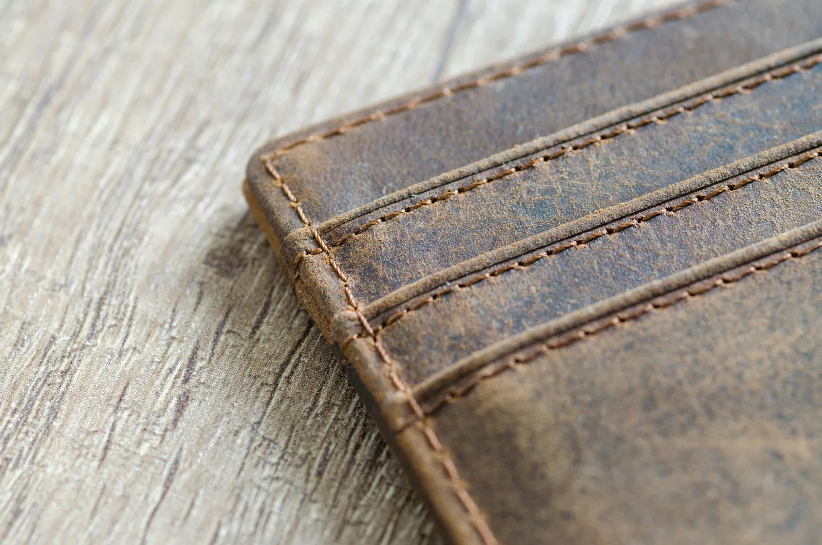 Close view of worn brown leather wallet stitching and surface texture