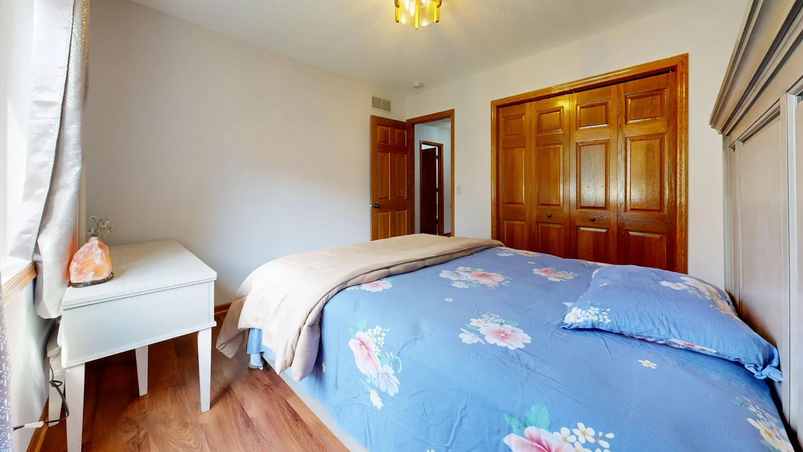 Bedroom with wooden wardrobe doors placed on the wall beside the bed