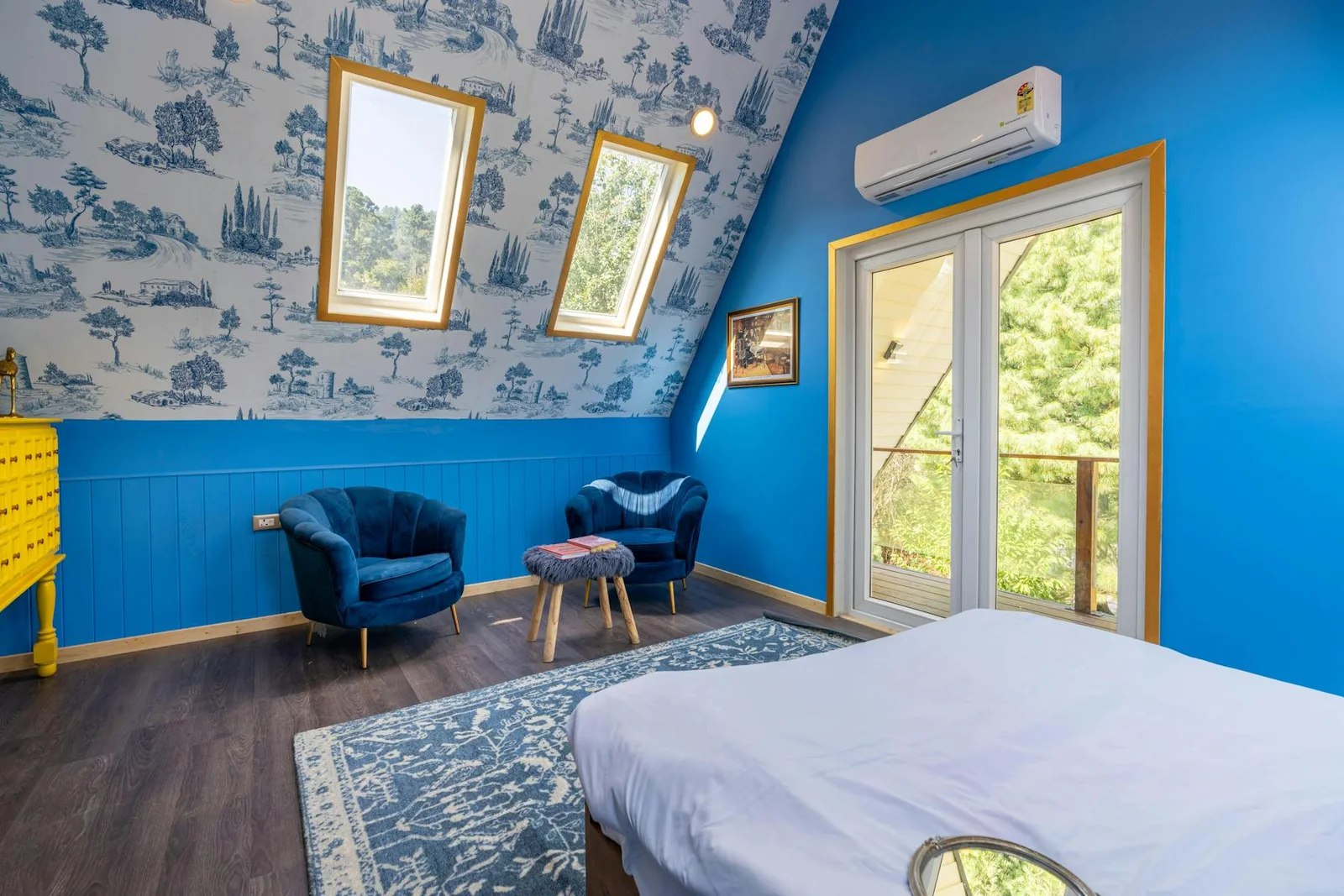 Bedroom with stronger blue wall treatment, blue chair, and bright window light