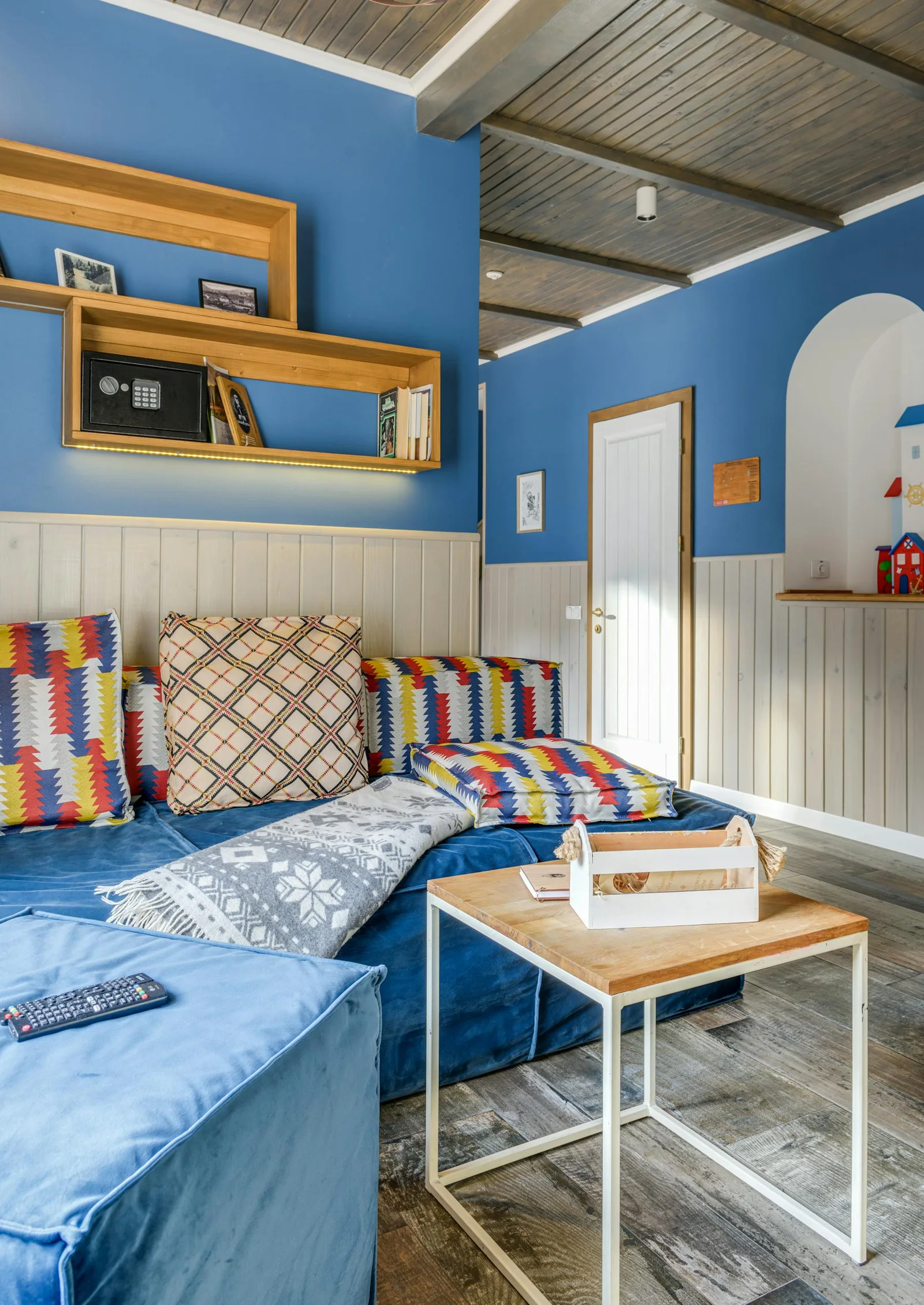 Living room with vivid blue wall, patterned textiles, and warm wood accents