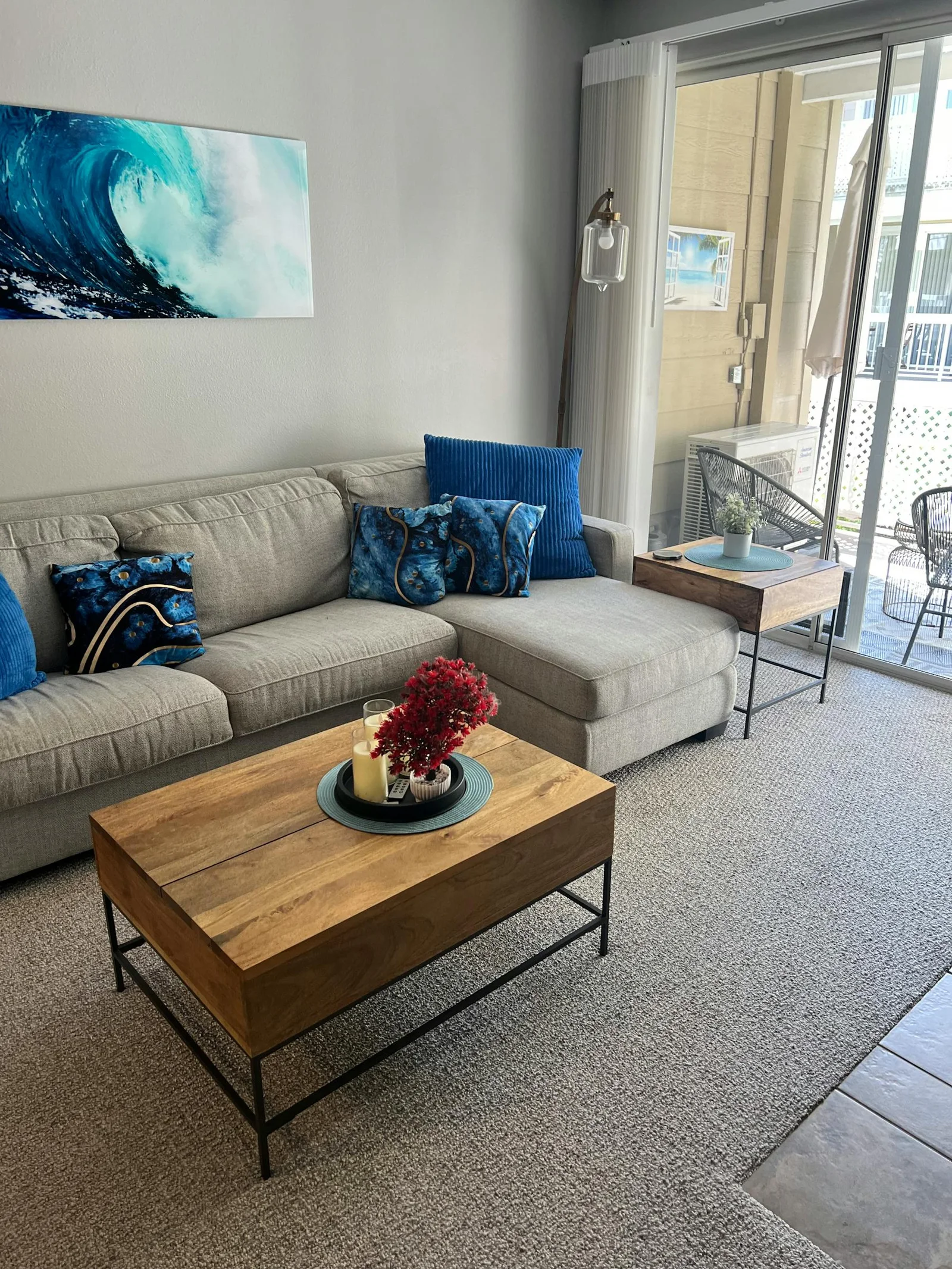 Living room with blue pillows, blue art, warm wood table, and soft neutral sofa