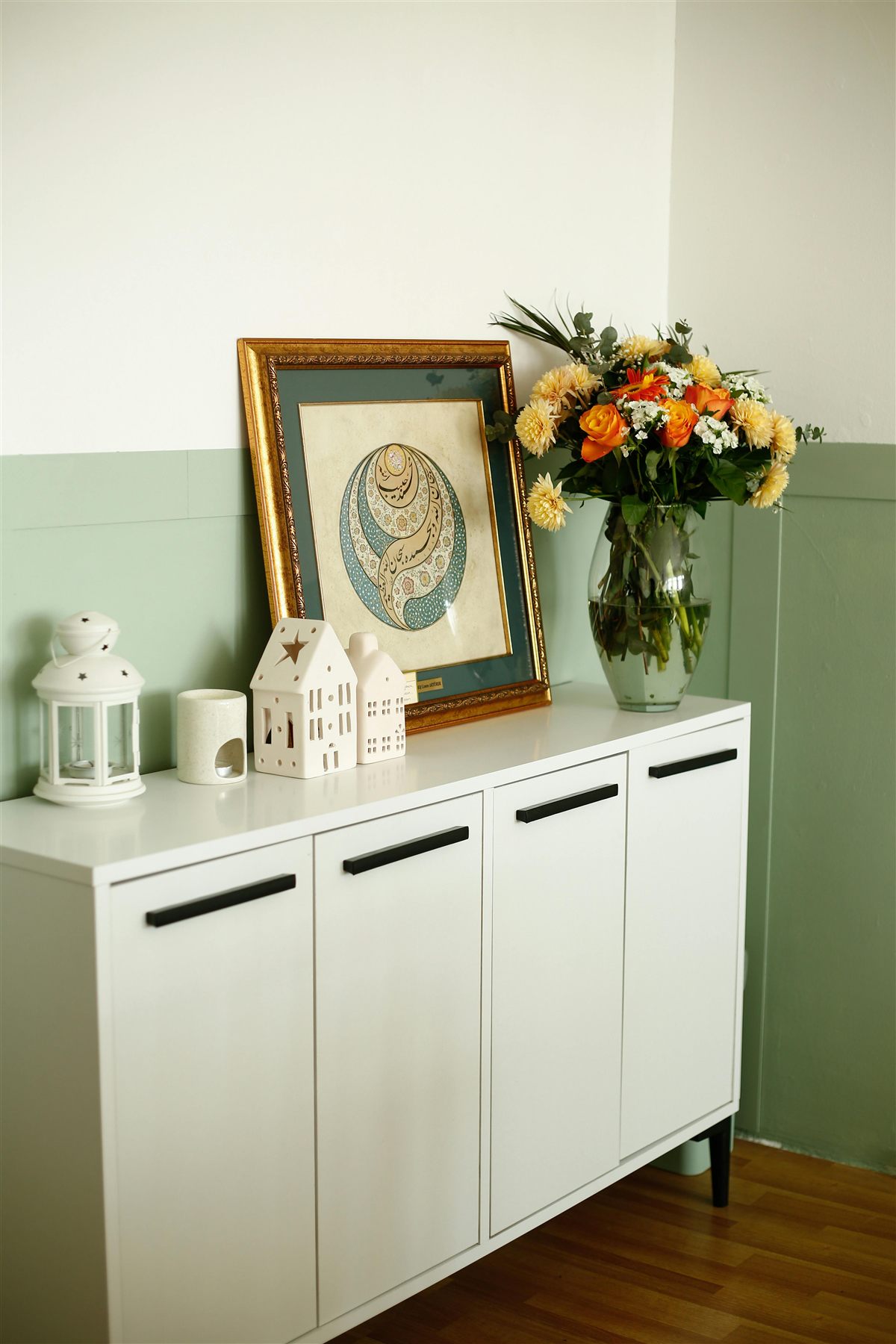 White console with art, flowers, and a few warm-toned decorative objects