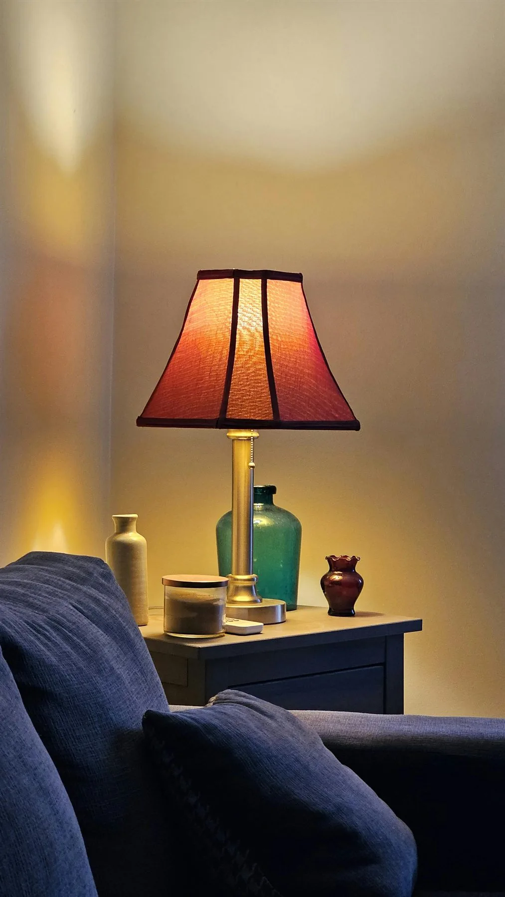 Warm table lamp glowing on a side table beside a sofa