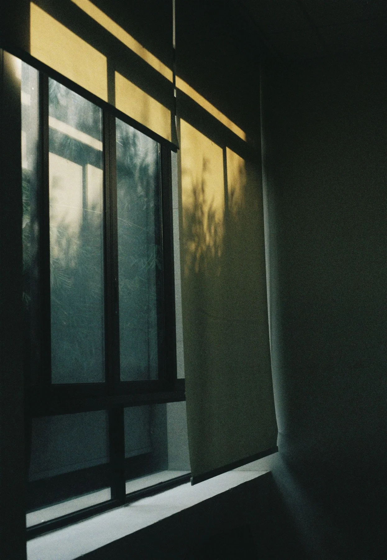 Partly lowered roller blind filtering warm sunlight through a window