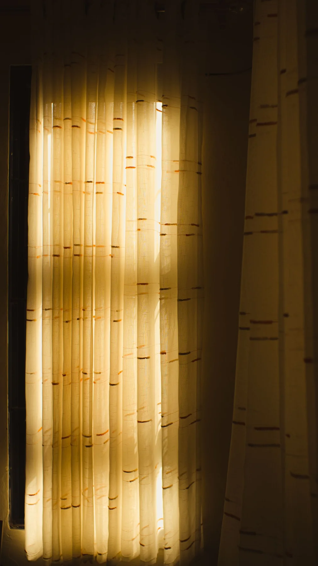 Warm sunlight filtered through a white sheer curtain beside a window