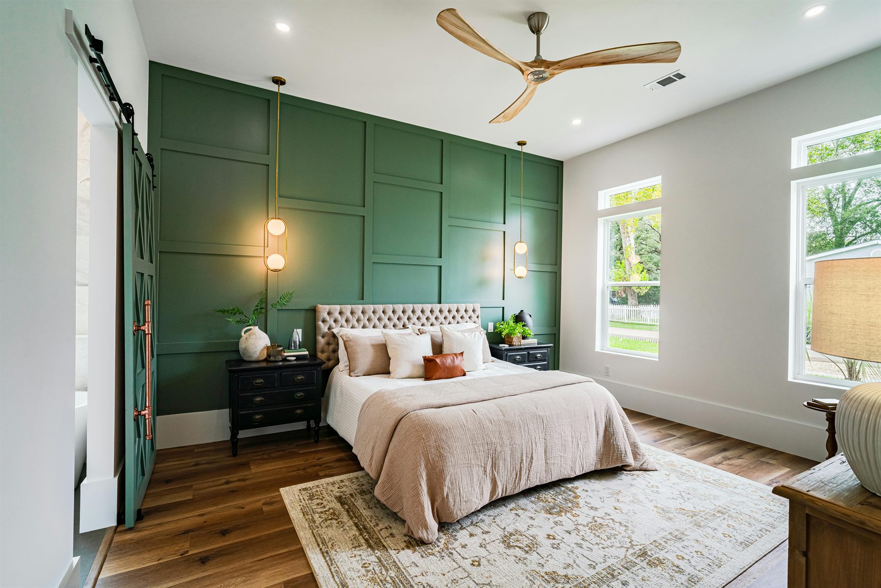 Green bedroom with layered bedding, wood, and a calm natural palette